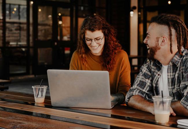 Des gens heureux devant un ordinateur portable comme symbole du divertissement de l'événement virtuel