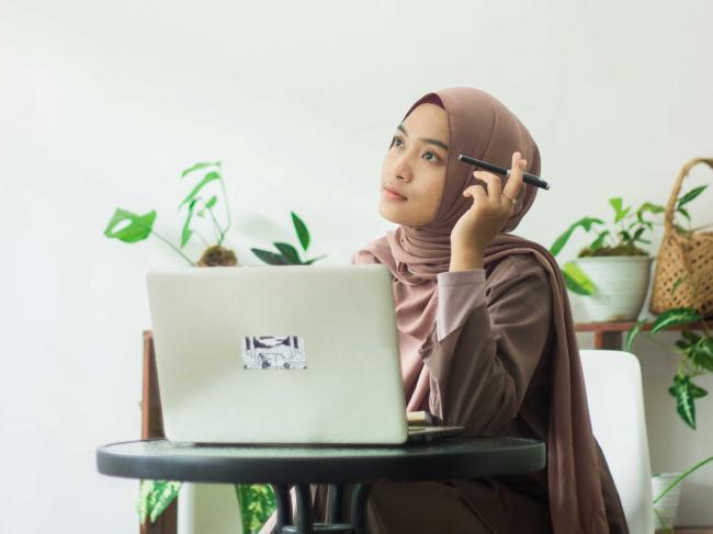 Femme réfléchie travaillant sur l'ordinateur portable