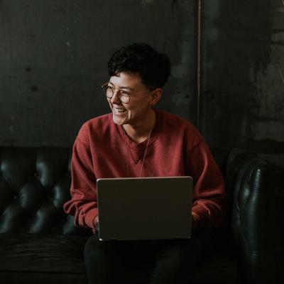 Happy woman sitting on sofa with laptop