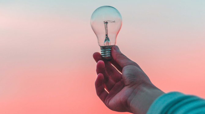 Glühbirne in Hand als Symbol für Innovation