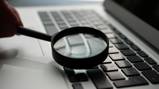 Computertastatur wird mit einer Lupe betrachtet Computertastatur wird mit einer Lupe betrachtet